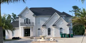 White house with dark gray roof and fountain in the front